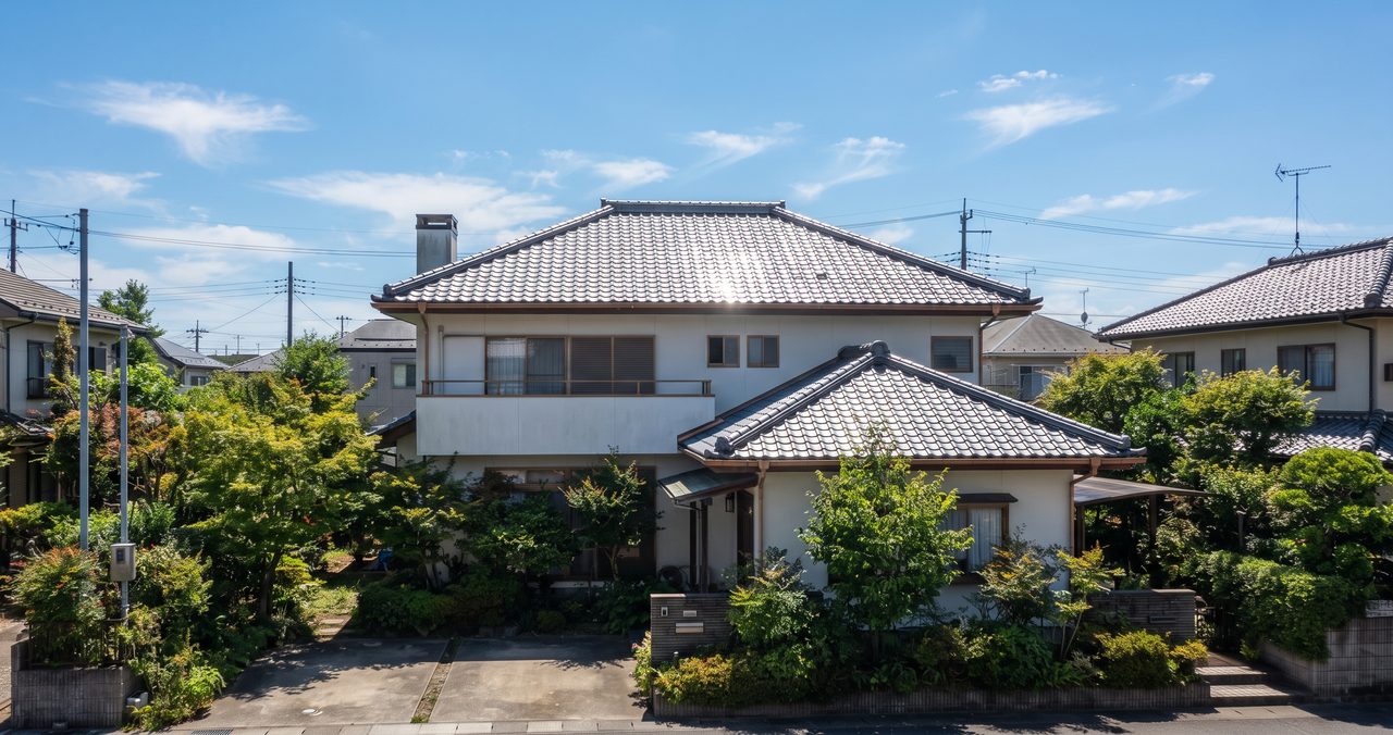 晴れた夏の日の戸建て住宅の屋根を少し離れた位置から写した外観写真、屋根表面に強い日差しが当たっている様子